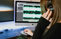 Une femme avec un casque audio regarde un écran avec des variations audio.